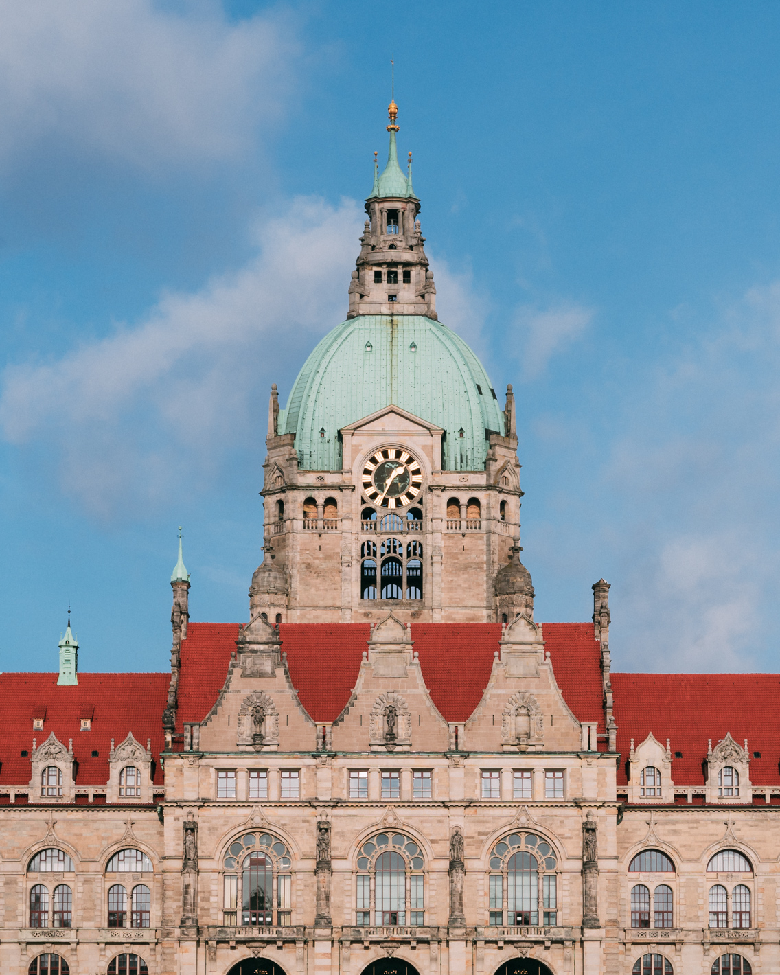 Neues Rathaus in Hannover mit markanter Kuppel und rotem Dach, fotografiert bei blauem Himmel.