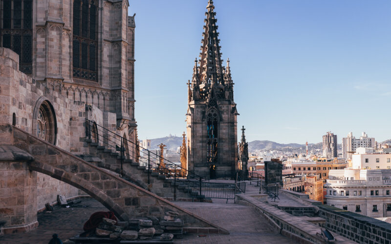 Dachterrasse der Kathedrale von Barcelona mit gotischem Turm und Blick über die Stadt bei klarem Himmel.