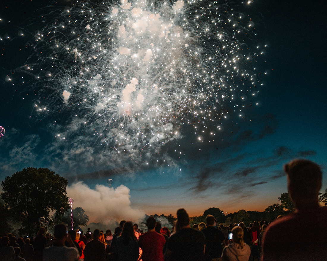 Großes Feuerwerk leuchtet am Nachthimmel über einer Menschenmenge während der Kieler Woche in Kiel.